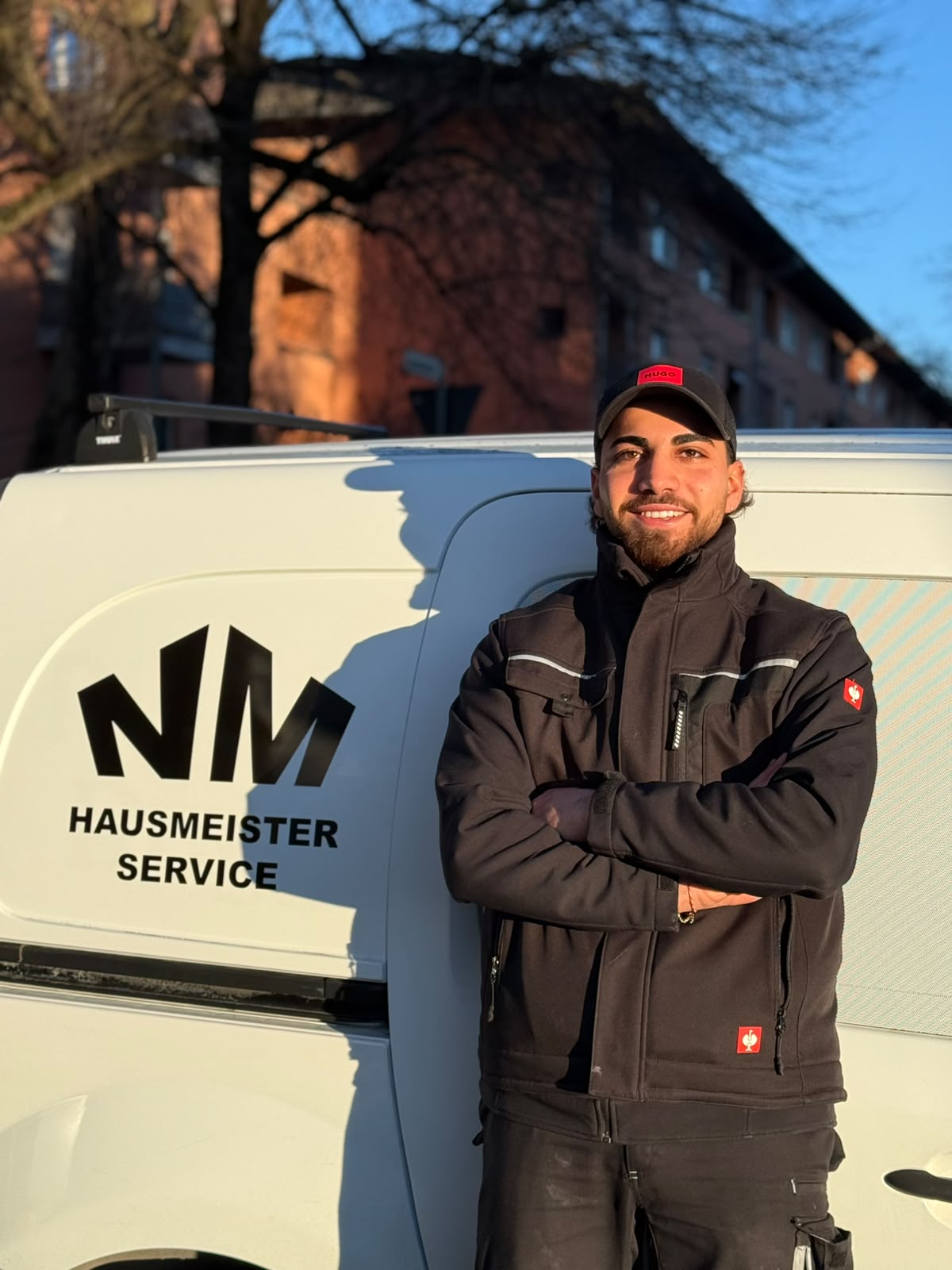 Ninos Michael Malke, Inhaber von NM Hausmeisterservice, vor dem Firmenfahrzeug in Augsburg